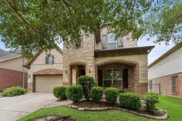 view of front of property with a front yard, brick siding, concrete driveway, an attached garage, and stone siding