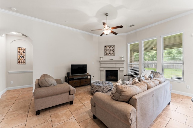living room featuring crown molding, visible vents, a fireplace, ceiling fan, and light tile patterned floors