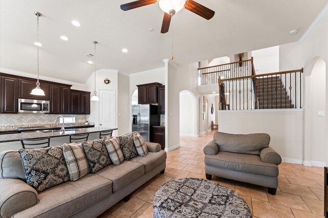 living room with ornamental molding, baseboards, ceiling fan, arched walkways, and light tile patterned floors