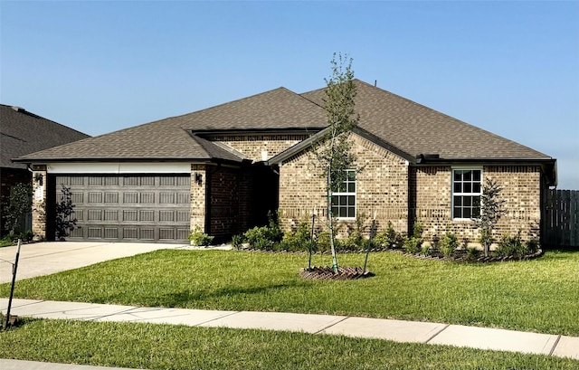 view of front facade with an attached garage, brick siding, concrete driveway, a front yard, and a shingled roof