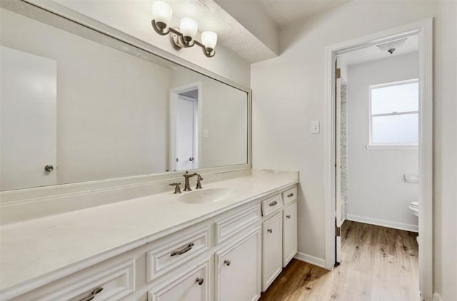 full bath featuring vanity, baseboards, toilet, and wood finished floors