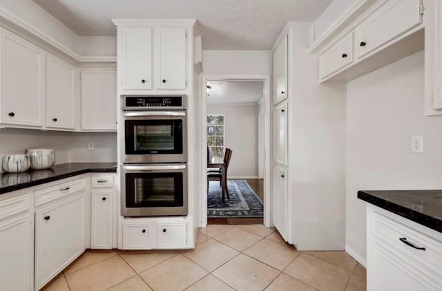 kitchen featuring white cabinets, double oven, a textured ceiling, and light tile patterned flooring