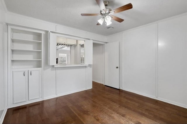 interior space featuring ceiling fan, a textured ceiling, visible vents, dark wood finished floors, and ornamental molding