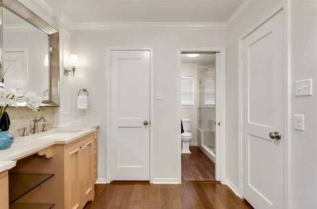 bathroom featuring vanity, crown molding, wood finished floors, toilet, and a shower stall