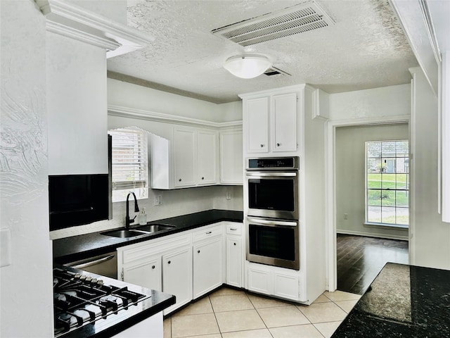 8315 Lichen Ln, Spring, TX 77379 - kitchen with stainless steel double oven, a sink, dark countertops, white cabinets, and gas stovetop