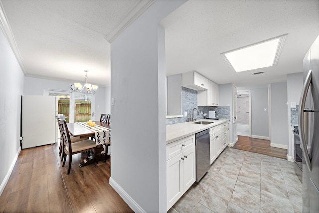 12633 Memorial Dr Unit 83, Houston, TX 77024 - kitchen with appliances with stainless steel finishes, an inviting chandelier, a sink, light countertops, and tasteful backsplash