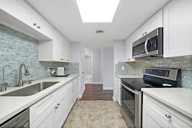12633 Memorial Dr Unit 83, Houston, TX 77024 - kitchen featuring backsplash, visible vents, a sink, stainless steel appliances, and white cabinetry