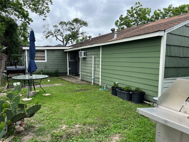 rear view of property featuring a lawn and a wall mounted AC