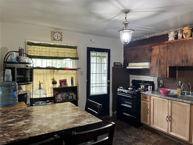 kitchen featuring a sink, under cabinet range hood, black gas range, and decorative light fixtures