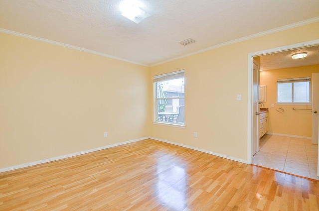 unfurnished room featuring light wood finished floors, plenty of natural light, ornamental molding, and baseboards