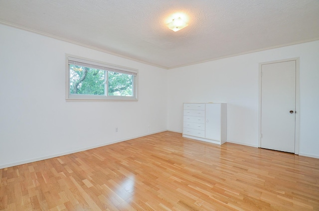 unfurnished room with light wood-style floors, ornamental molding, and baseboards