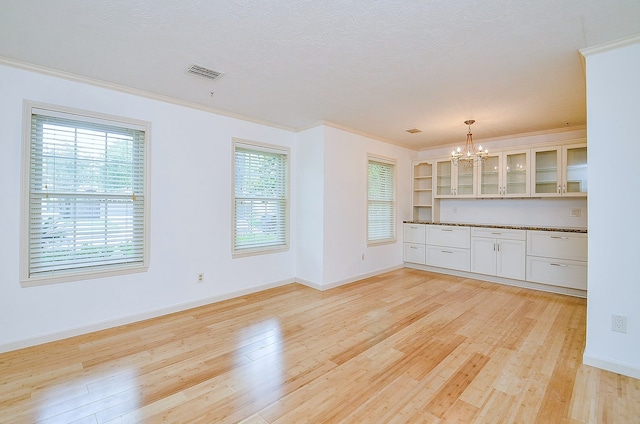 1915 Ashford Hollow Ln, Houston, TX 77077 - kitchen with dark countertops, a chandelier, glass insert cabinets, light wood-type flooring, and ornamental molding