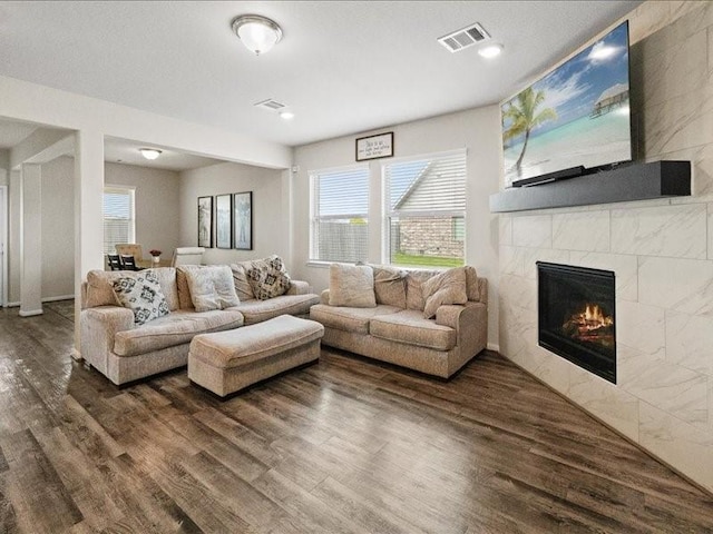 living room featuring a tile fireplace, wood finished floors, and visible vents