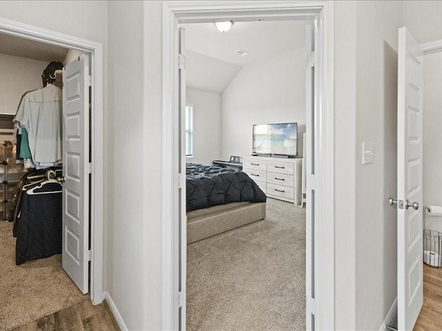 interior space featuring carpet flooring, baseboards, wood finished floors, and lofted ceiling