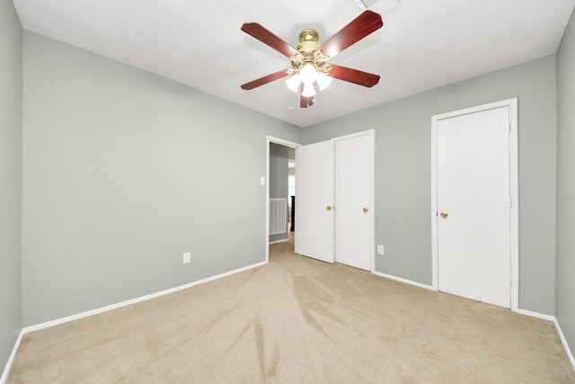 unfurnished bedroom with carpet floors, visible vents, two closets, baseboards, and a ceiling fan