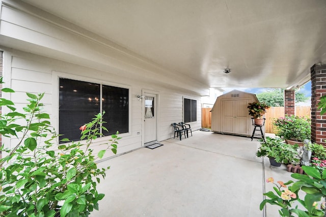 view of patio / terrace with a storage shed, fence, and an outbuilding