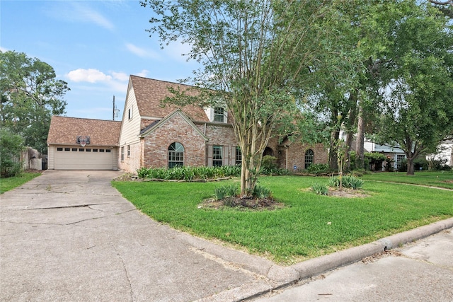 tudor-style house with a shingled roof, a front lawn, brick siding, a garage, and driveway