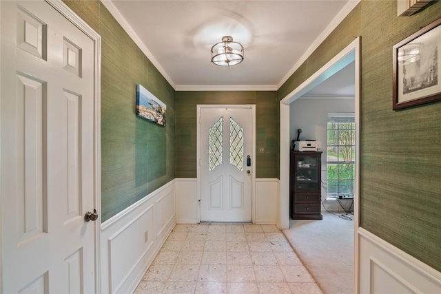 foyer entrance with light floors, ornamental molding, wainscoting, and wallpapered walls