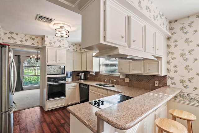 kitchen featuring visible vents, wallpapered walls, a sink, dark wood finished floors, and black appliances