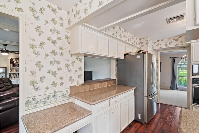 kitchen with visible vents, freestanding refrigerator, wallpapered walls, dark wood-type flooring, and white cabinetry