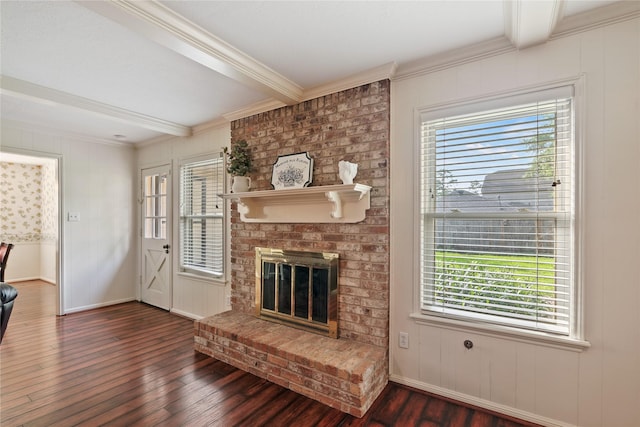 unfurnished living room with beam ceiling, a brick fireplace, ornamental molding, baseboards, and dark wood-style floors