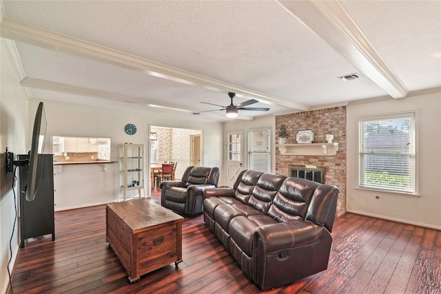 living room with crown molding, ceiling fan, a fireplace, dark wood-type flooring, and beamed ceiling