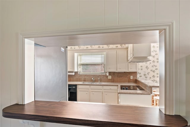 kitchen with a sink, white cabinets, backsplash, and black appliances