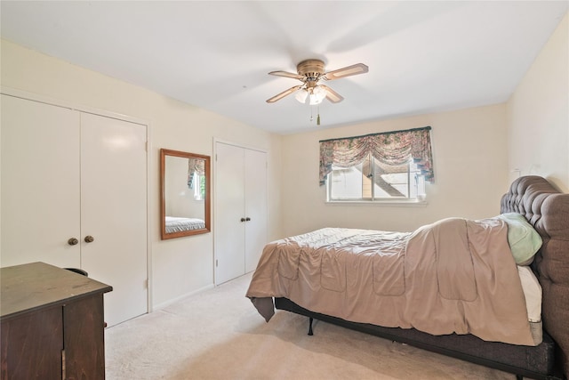 bedroom featuring two closets, ceiling fan, and light carpet