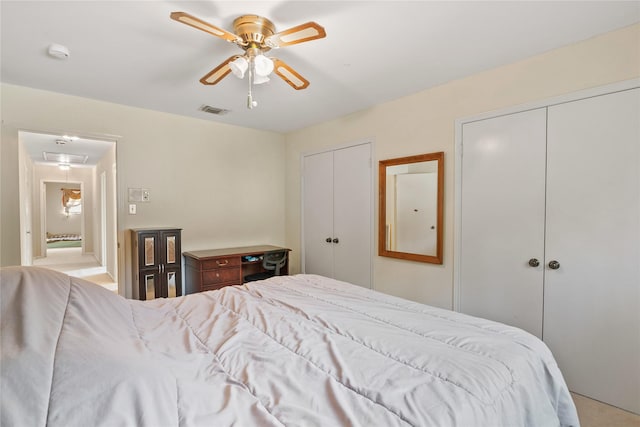 bedroom featuring two closets, a ceiling fan, visible vents, and attic access