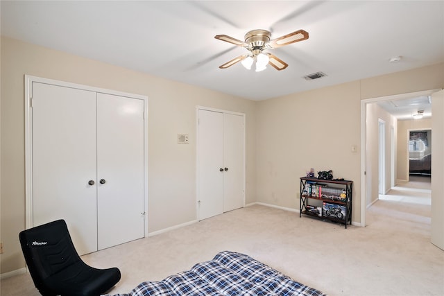 bedroom with attic access, visible vents, light colored carpet, baseboards, and multiple closets