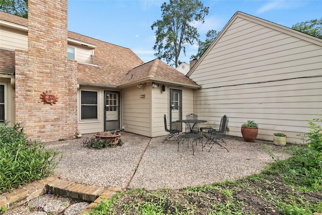 back of house with a patio, a fire pit, a shingled roof, and a chimney