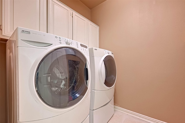 2111 Welch St Unit B117, Houston, TX 77019 - washroom featuring light tile patterned floors, baseboards, cabinet space, and washing machine and clothes dryer