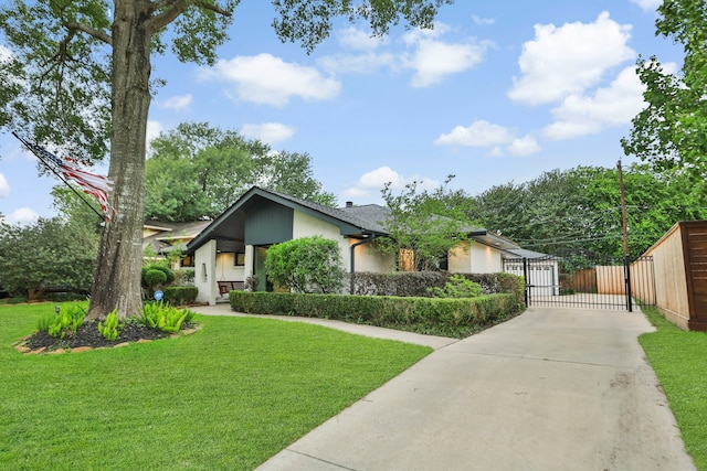 view of front of property featuring driveway, a gate, fence, a front lawn, and stucco siding