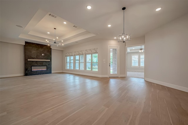 unfurnished living room featuring visible vents, a raised ceiling, baseboards, and a chandelier