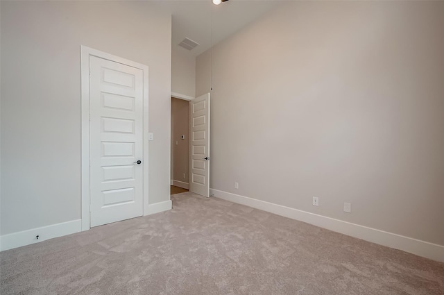 unfurnished bedroom featuring visible vents, baseboards, high vaulted ceiling, and light carpet