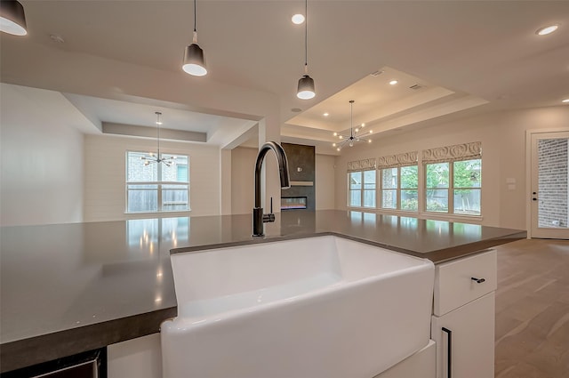 kitchen featuring dark countertops, an inviting chandelier, a sink, and a raised ceiling