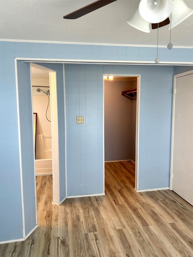 16717 Captain Hook, Jamaica Beach, TX 77554 - unfurnished bedroom featuring a closet, a ceiling fan, a walk in closet, and wood finished floors