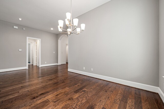 empty room with arched walkways, recessed lighting, a chandelier, baseboards, and dark wood-style flooring