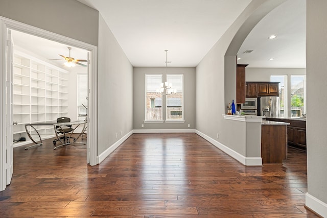 unfurnished dining area featuring dark wood-style flooring, arched walkways, a desk, baseboards, and recessed lighting