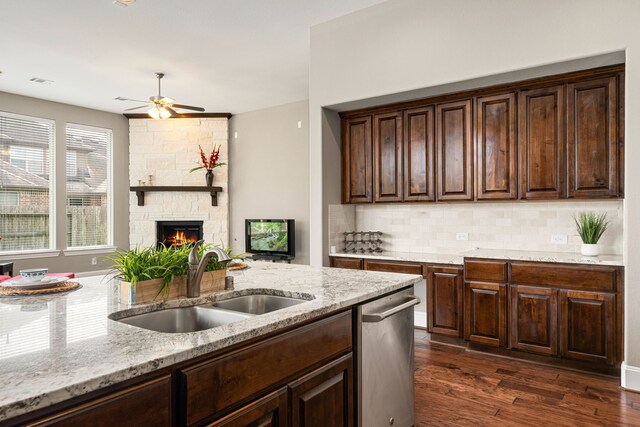 kitchen with a sink, dishwasher, light stone counters, tasteful backsplash, and dark brown cabinetry