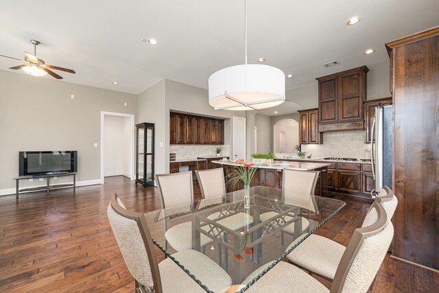 dining area featuring arched walkways, ceiling fan, dark wood-style floors, recessed lighting, and baseboards