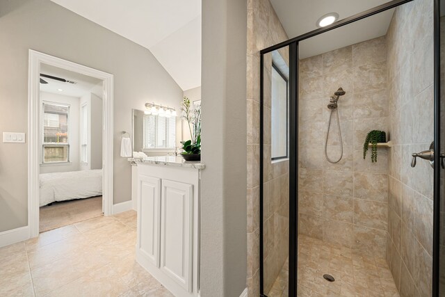ensuite bathroom featuring a stall shower, vanity, tile patterned flooring, baseboards, and lofted ceiling