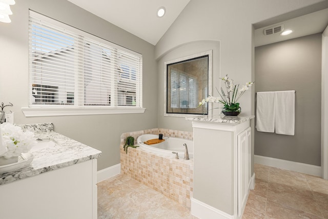 full bathroom with a garden tub, vaulted ceiling, vanity, baseboards, and tile patterned floors