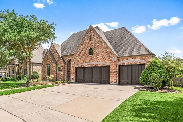 view of front of home featuring brick siding, roof with shingles, a front lawn, and concrete driveway