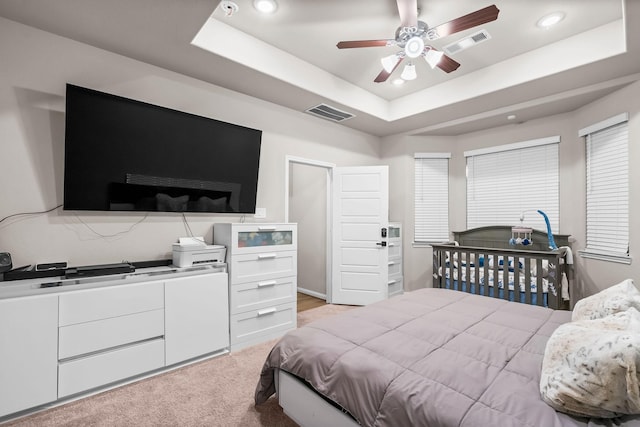 bedroom with a tray ceiling, visible vents, and recessed lighting