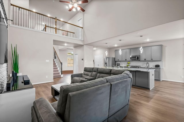living room featuring stairs, recessed lighting, light wood finished floors, a ceiling fan, and baseboards