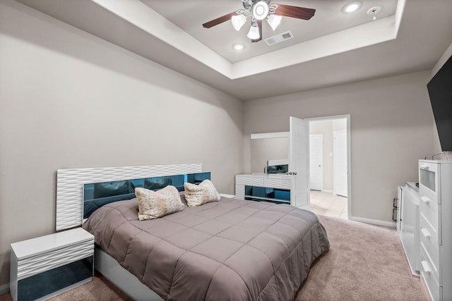 carpeted bedroom with a tray ceiling, recessed lighting, baseboards, ceiling fan, and visible vents