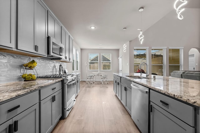 kitchen featuring stainless steel appliances, a sink, decorative backsplash, and gray cabinets