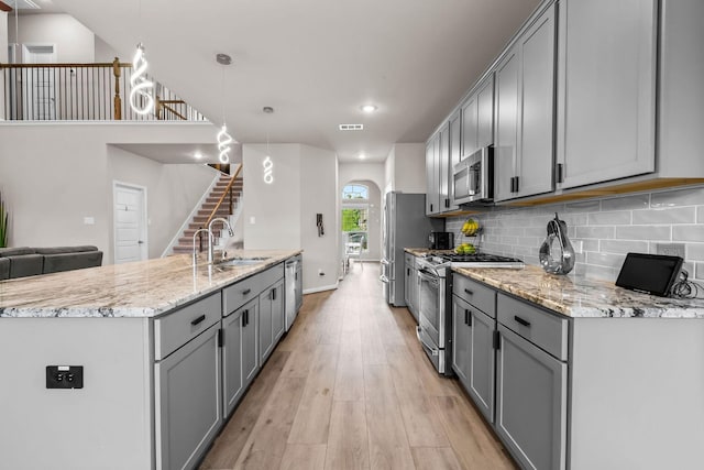 kitchen with a sink, stainless steel appliances, and gray cabinetry