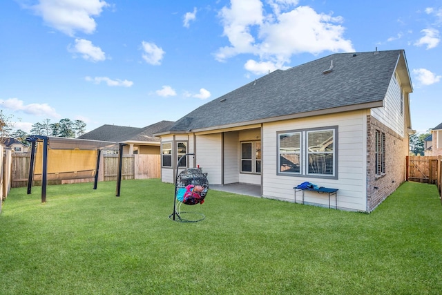 rear view of house with a fenced backyard, a shingled roof, a patio, and a lawn